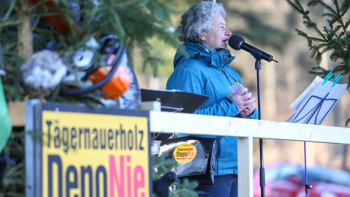 Eine Frau spricht auf einem Podium im Wald.